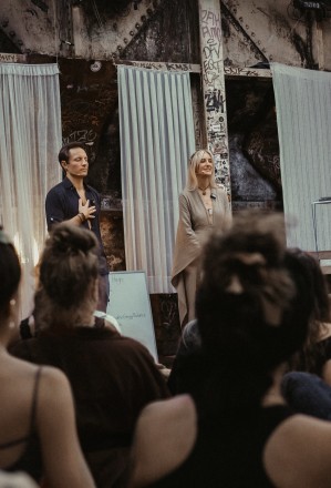 Leslie and Marc, founders of WildHugs intimacy events and coaching, publicly speaking to an audience